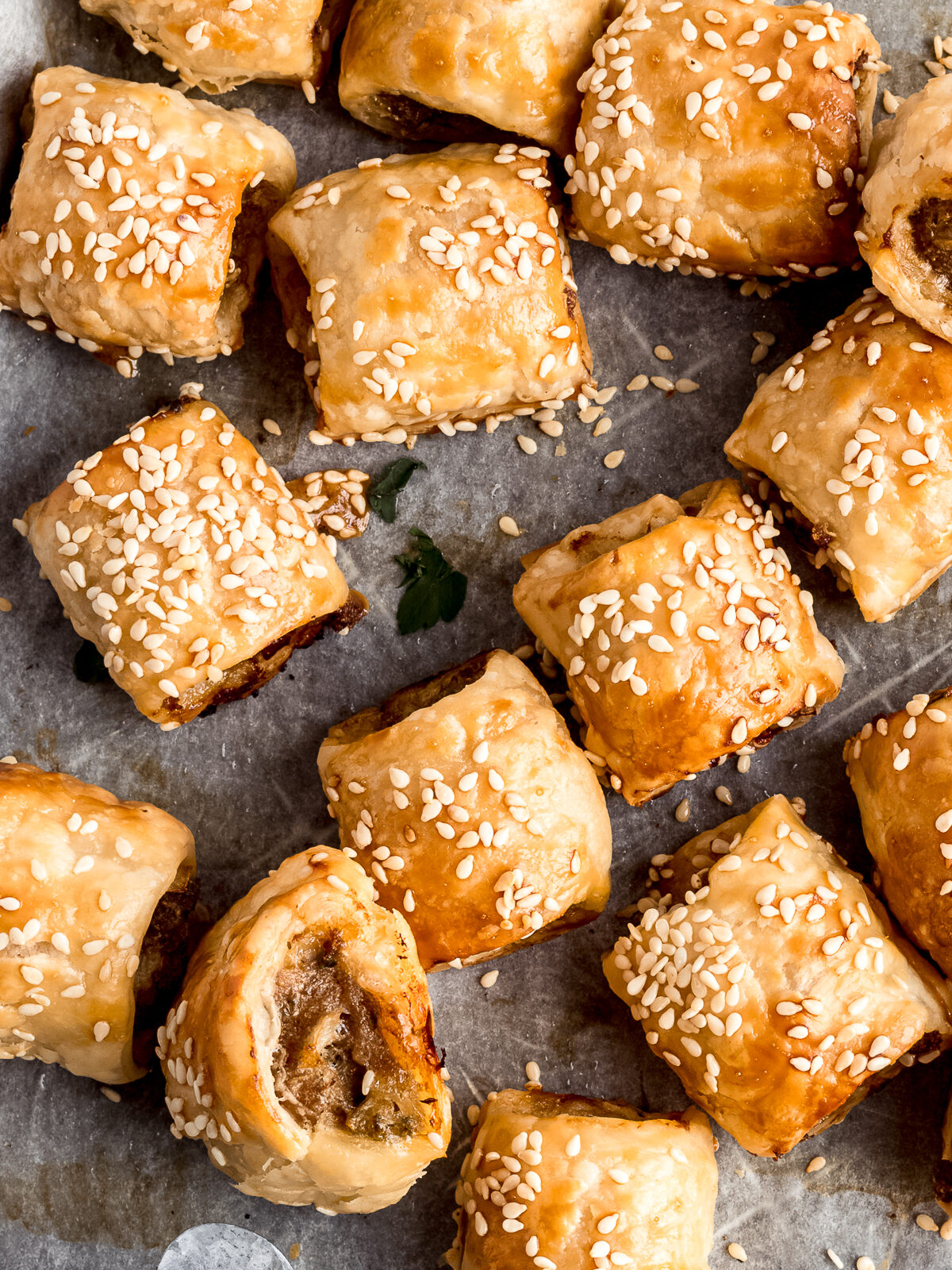 Crispy golden homemade sausage rolls on a tray with tomato sauce.
