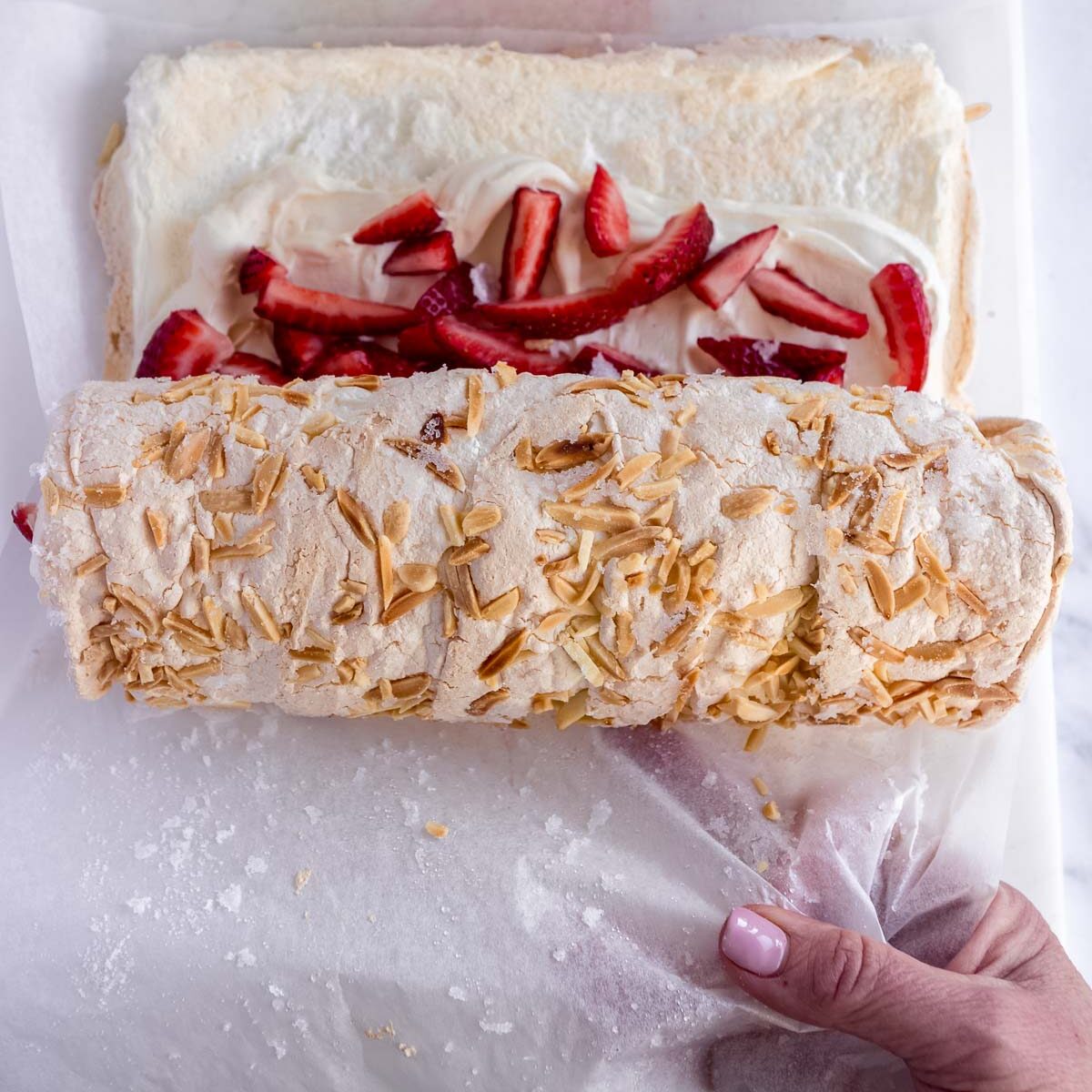 How to roll a pavlova, by gently lifting up with baking paper.