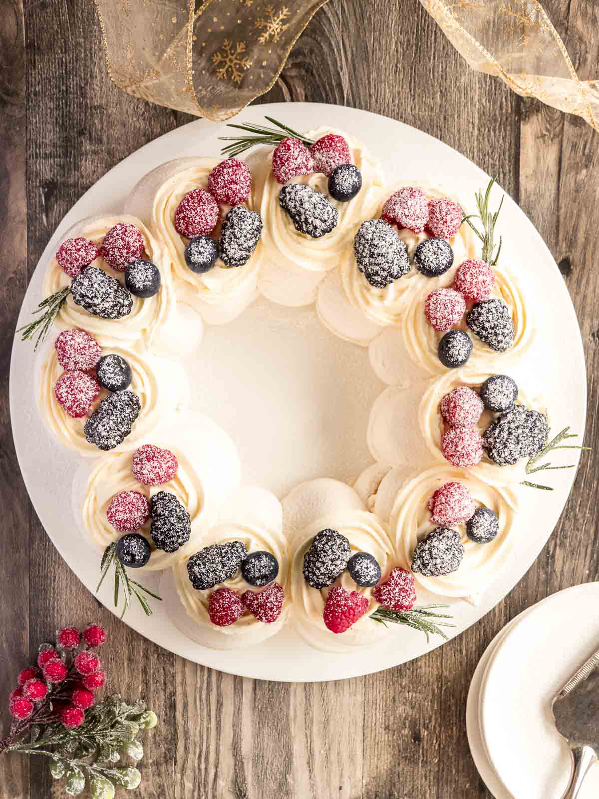 Crispy, marshmallow-filled pavlova wreath, perfect for Christmas.  Decorated with fresh berries and icing sugar.