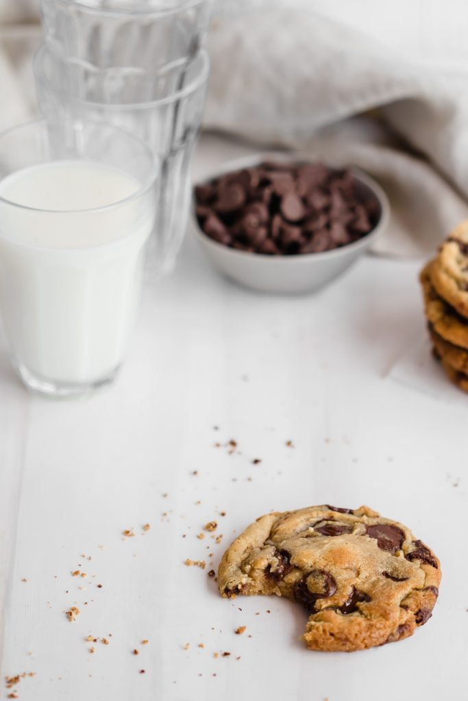half eaten chocolate chip cookie with glass of milk