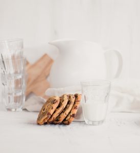 4 chocolate chip cookies on a glass of milk