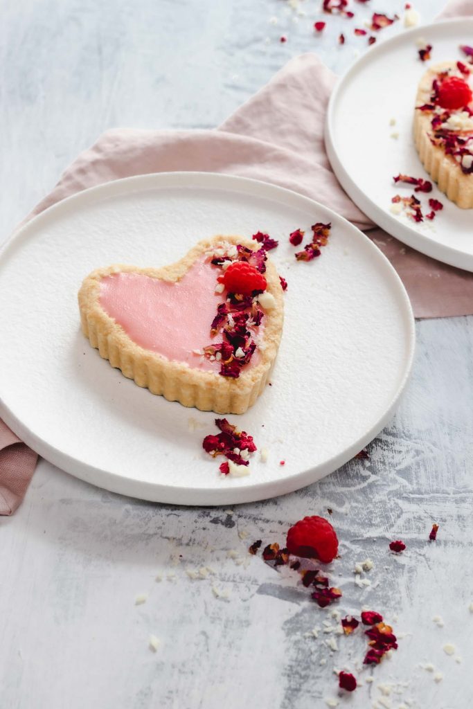 pink chocolate heart shaped tarts sprinkled with rose petals