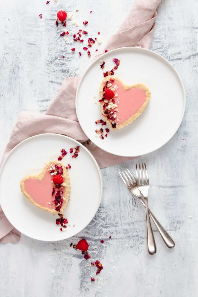 pink heart shaped chocolate tarts on white plates with a pink napkin