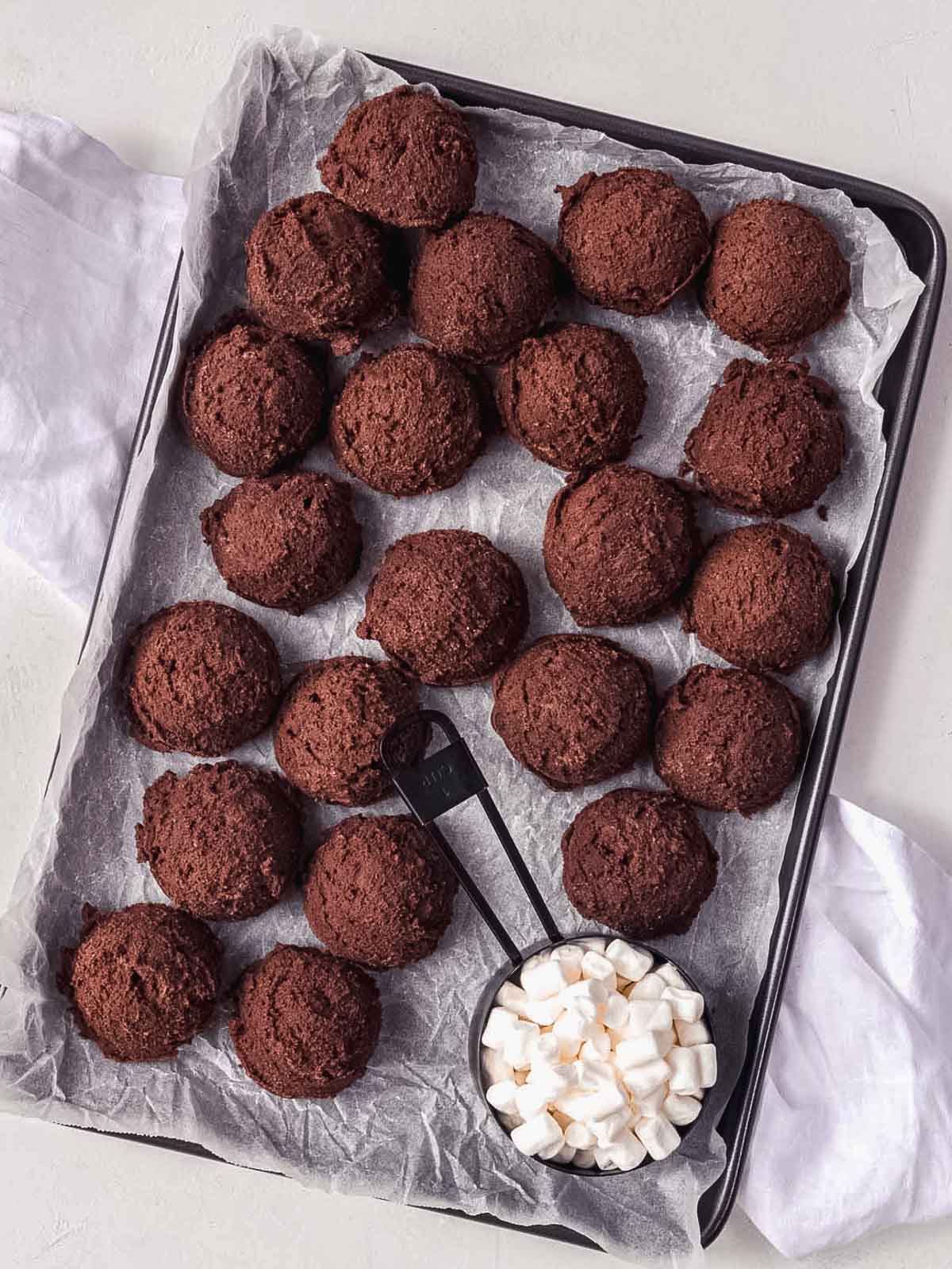 Chocolate marshmallow cookie dough balls on baking tray, sealed to prevent marshmallow leaking.