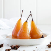 3 spiced vanilla poached pears in poaching liquid.