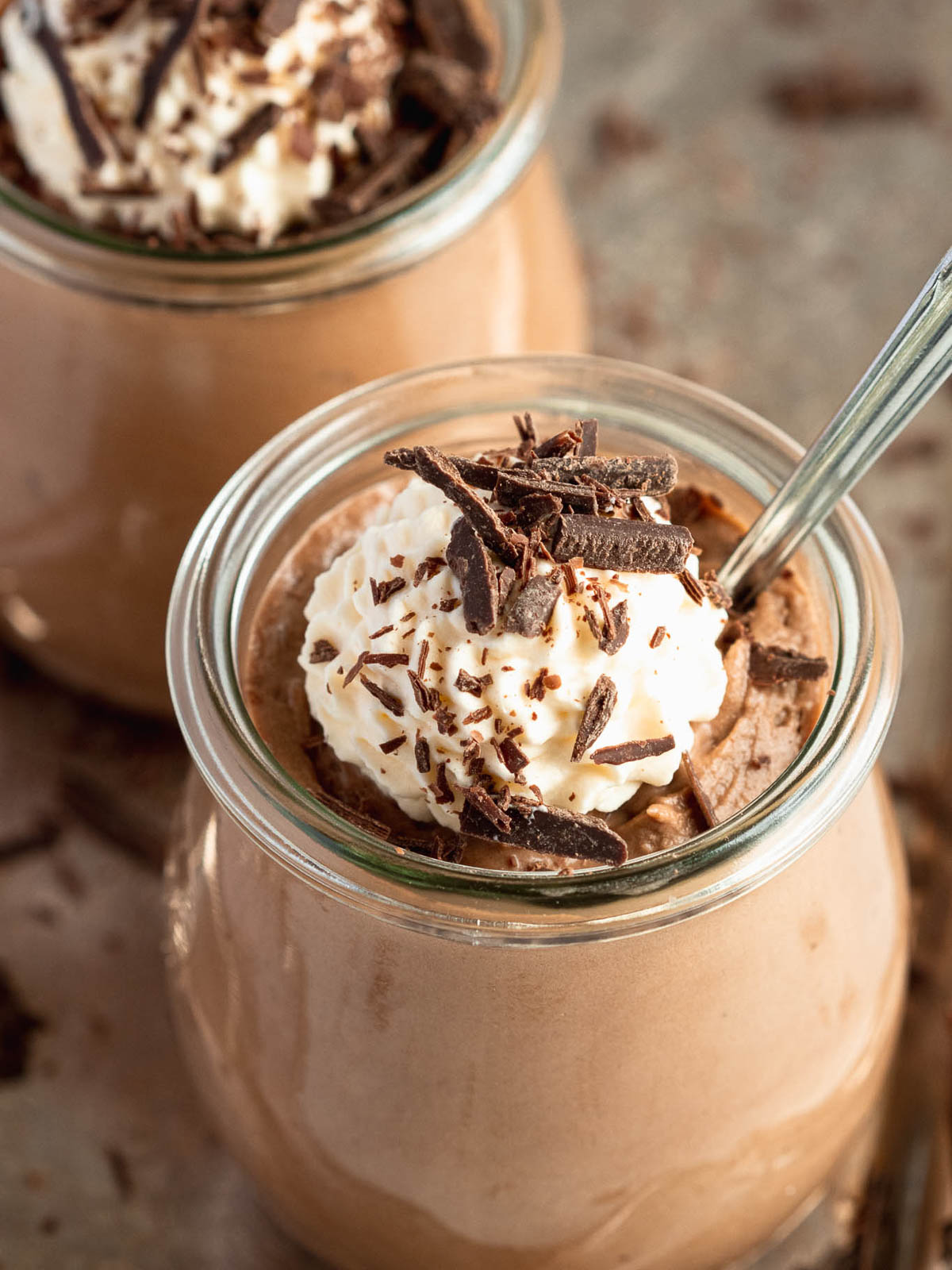 Toblerone mousse served in a small glass jar, topped with whipped cream and chocolate shavings. 