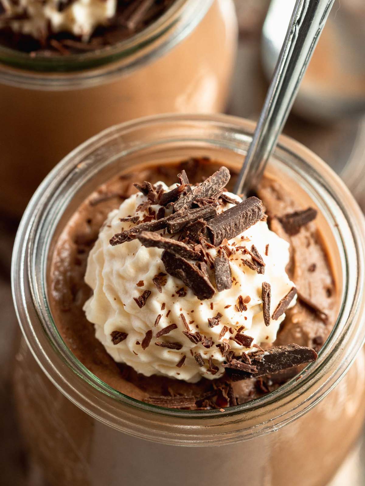 Toblerone mousse served in a small glass jar, topped with whipped cream and chocolate shavings. 