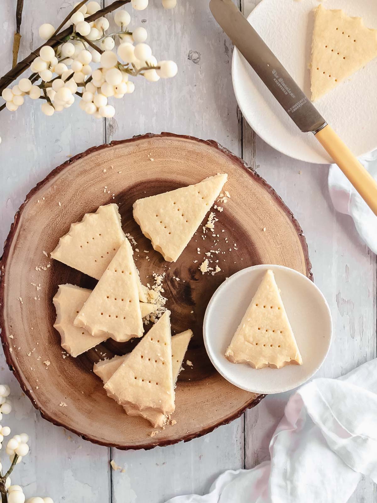 Wedges of Christmas shortbread on a rustic wooden cake stand, golden and sugar-dusted, ready to share
