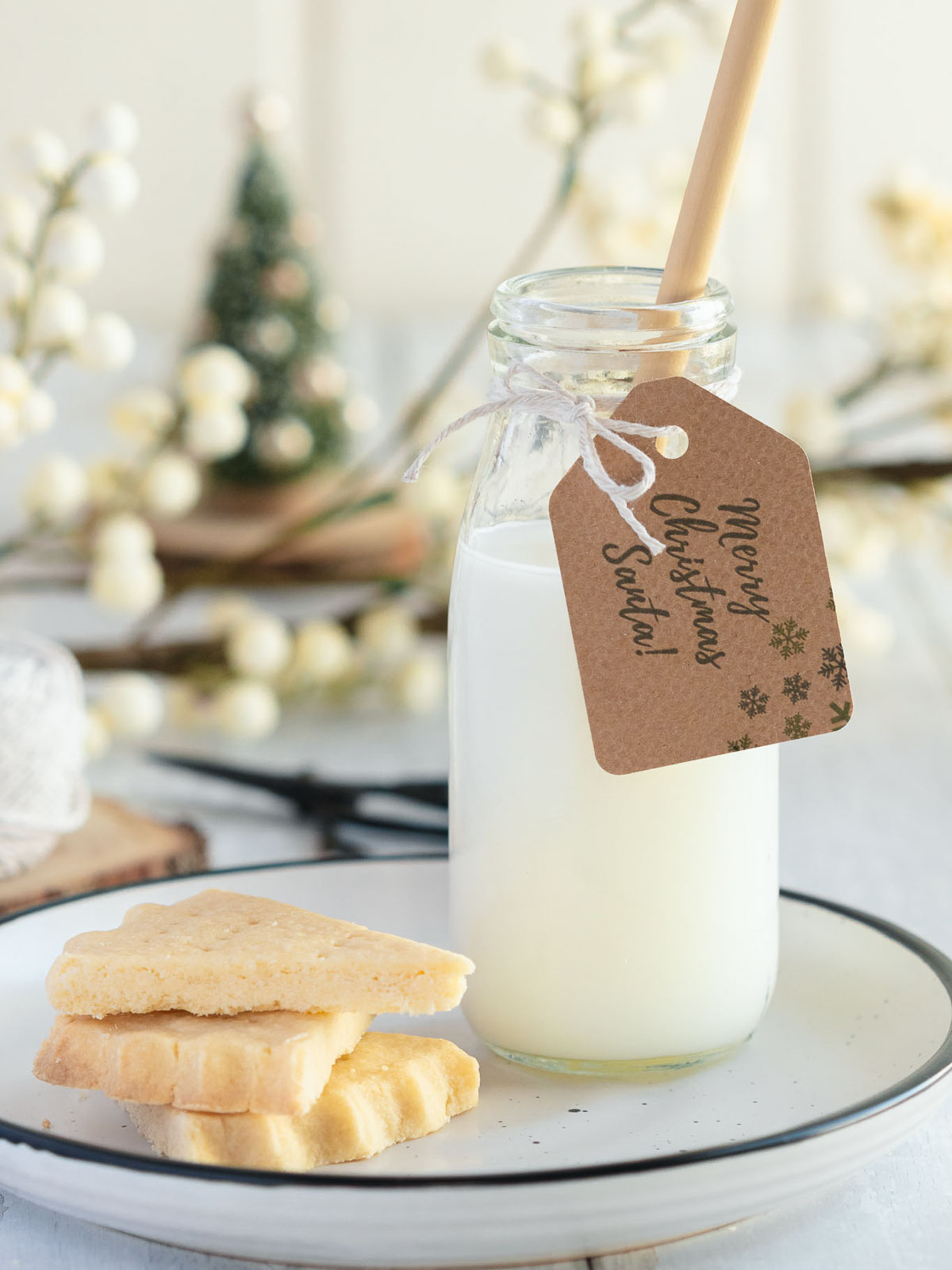 Classic shortbread served on a china plate with a bottle of milk, surrounded by Christmas baubles and fairy lights