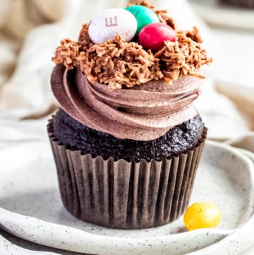 single chocolate cupcake with swirls chocolate frosting topped with coconut nest and easter eggs