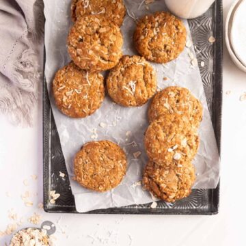 tray of ANZAC cookies with a bottle of milk and plates
