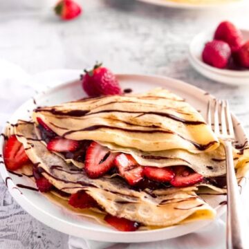 2 crepes filled with strawberries and nutella and drizzled with chocolate