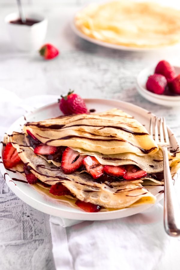 2 crepes filled with strawberries and nutella and drizzled with chocolate