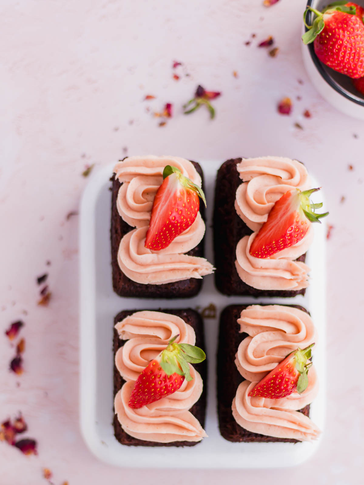 Four mini chocolate cakes decorated with fresh strawberry buttercrea.