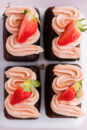 Four mini chocolate cakes with fluffy strawberry buttercream.
