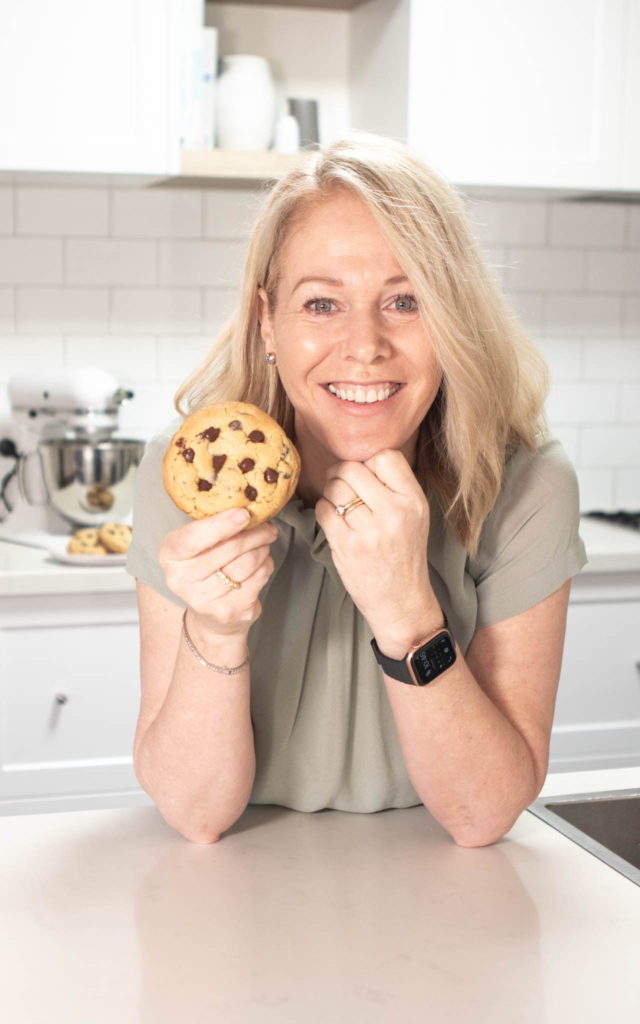 Apple cake Annie holding up a giant chocolate chip cookie.