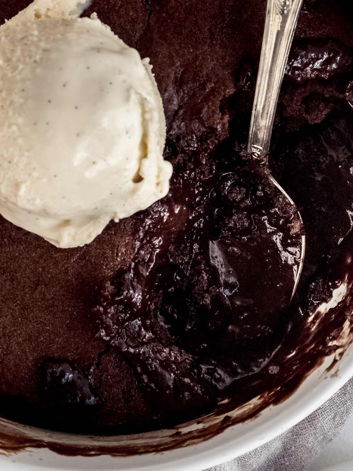 close up of chocolate self-saucing pudding and a scoop of vanilla ice cream.