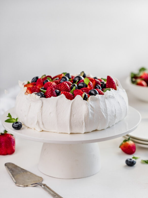 pavlova on a tall cake stand, decorated with fresh berries