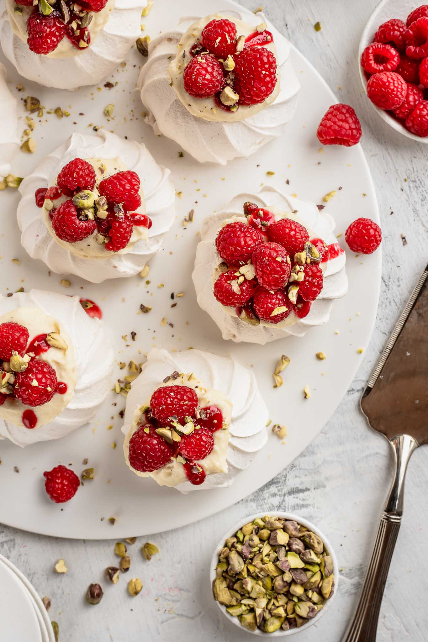 4 mini pavlovas decorated with raspberries and pistachios