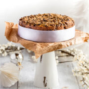plain Christmas cake on a cake stand and a white ribbon around the outside