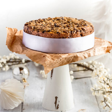 plain Christmas cake on a cake stand and a white ribbon around the outside