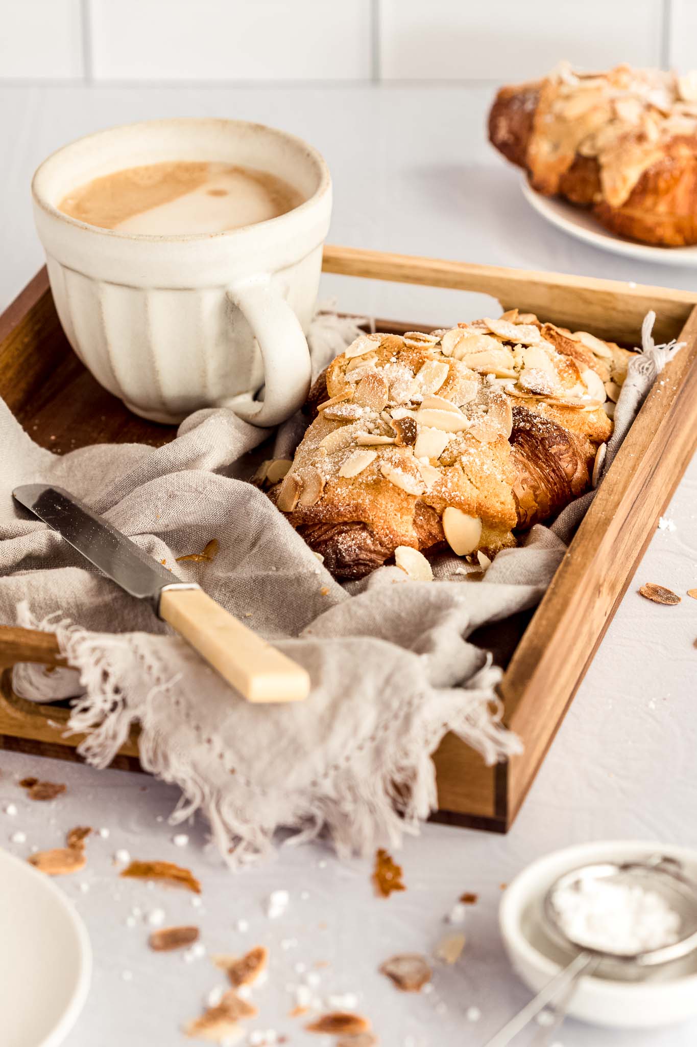 almond croissant on a tray with a knife and a coffee