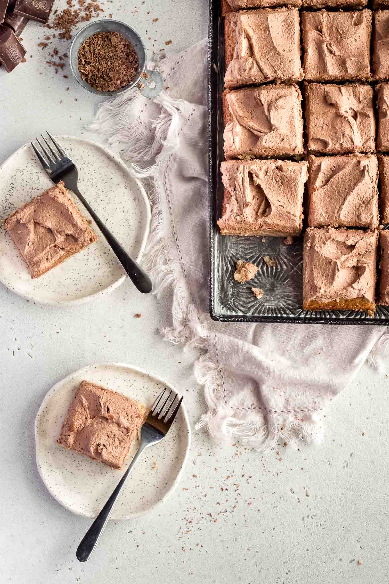 a sheet pan with banana cake squares topped with chocolate buttercream