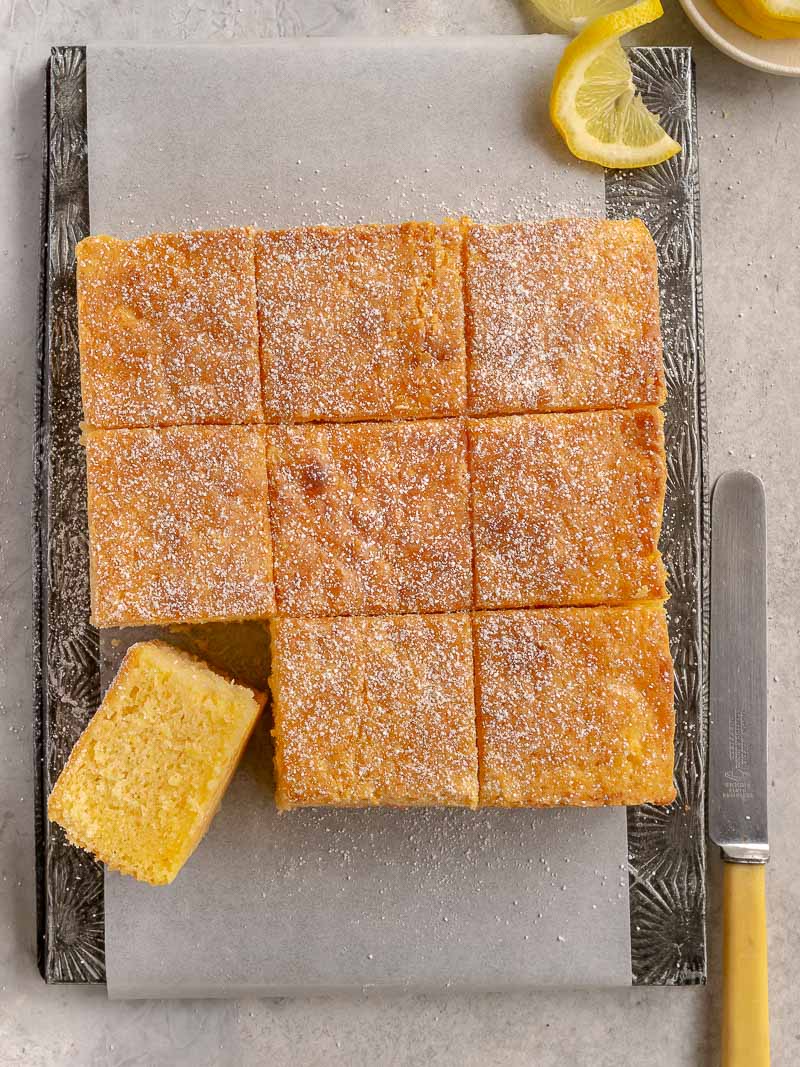 a square easy lemon sour cream cake cut into 9 smaller squares and dusted with powdered sugar