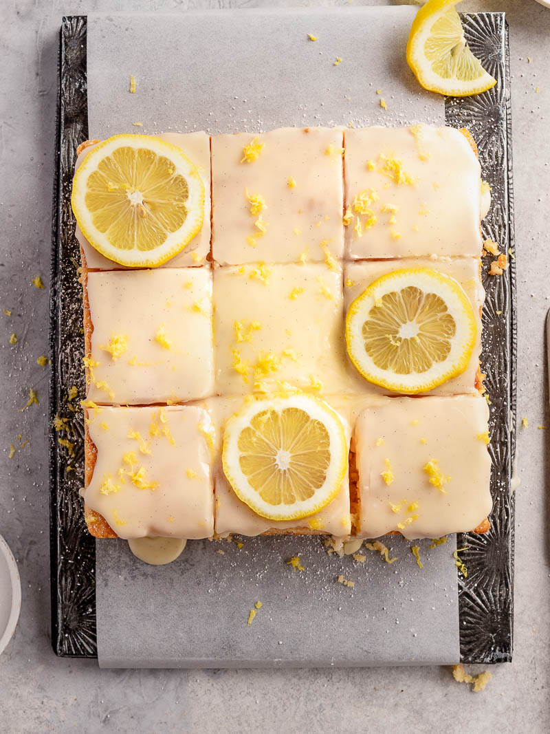 easy lemon sour cream cake covered with vanilla bean glaze and sprinkled with lemon zest and lemon slices