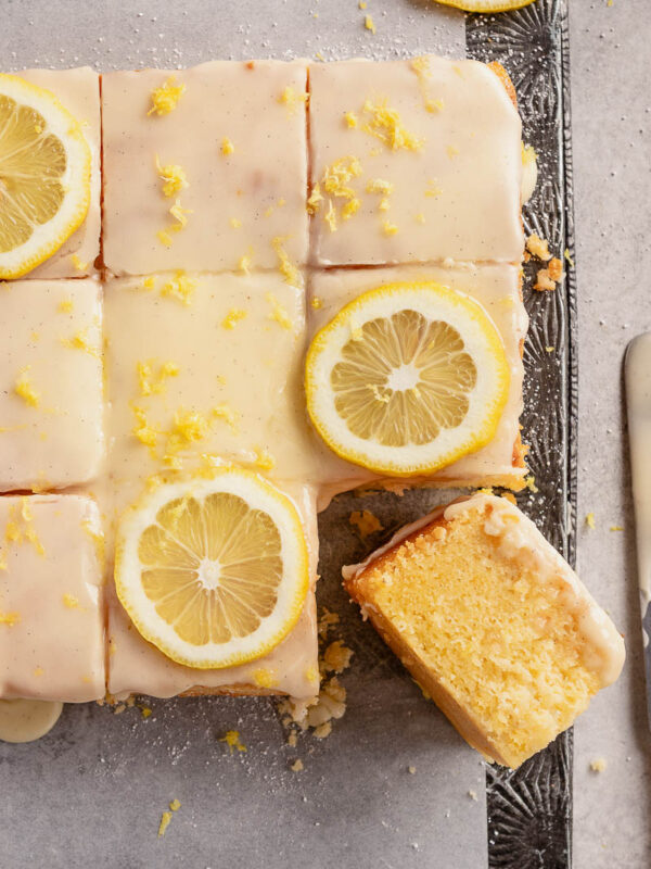 easy lemon sour cream cake, covered with vanilla bean glaze and decorated with lemon slices and lemon zest