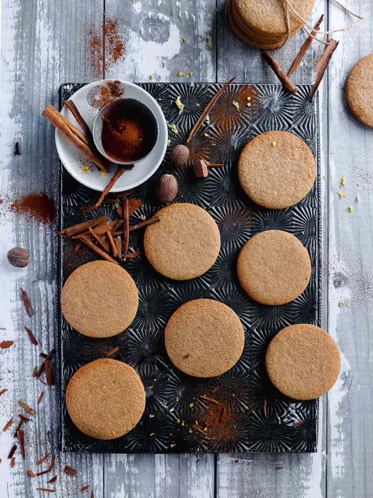 a vintage tray with 7 plain speculaas sugar cookies and a small white bowl filled with spice mix on the side