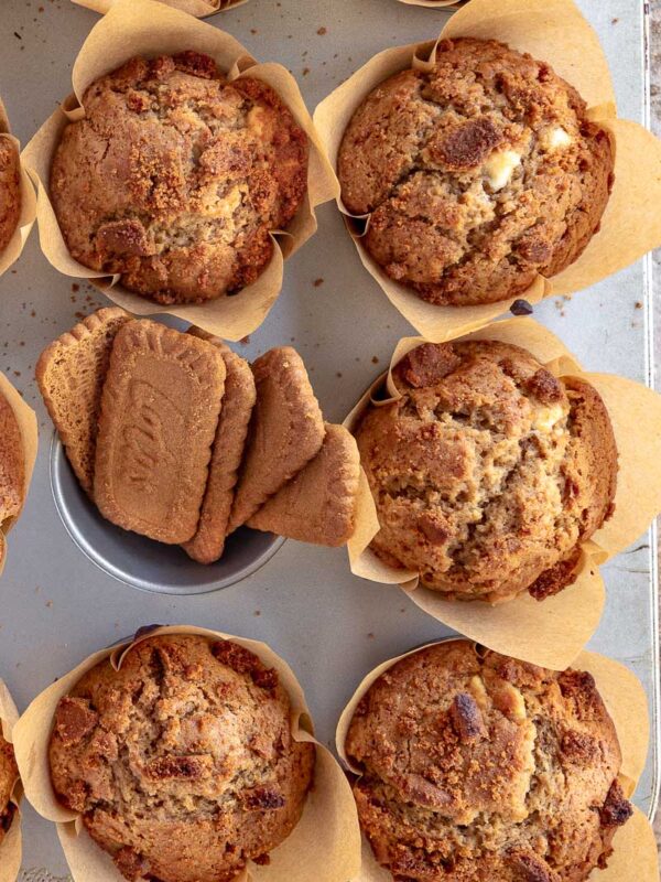 close up of easy biscoff muffins in a muffin tin, with 4 biscoff biscuits in one cavity