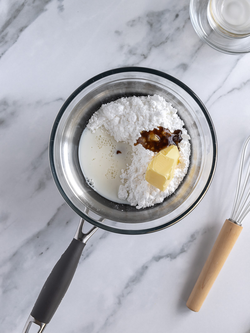 ingredients used to make easy vanilla bean glaze, all placed into a glass bowl