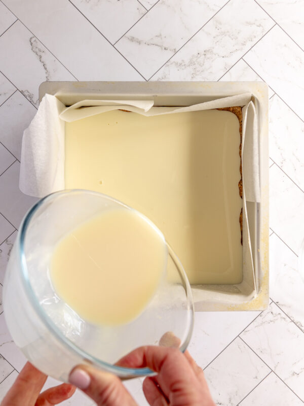 pouring condensed mil layer onto biscuit base