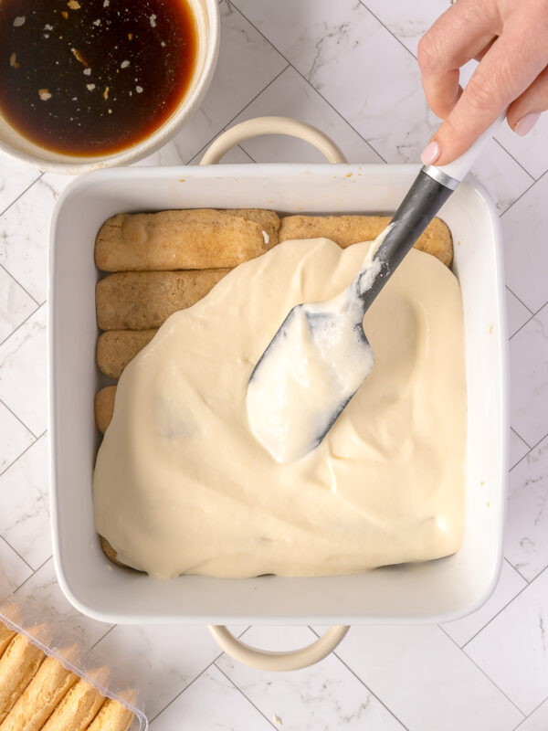 spreading mascarpone mixture over lady finger biscuits