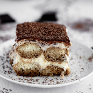 a single serve of Tiramisu sits on a white plate