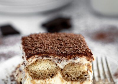 single serve of tiramisu on a white plate, with a vintage fork