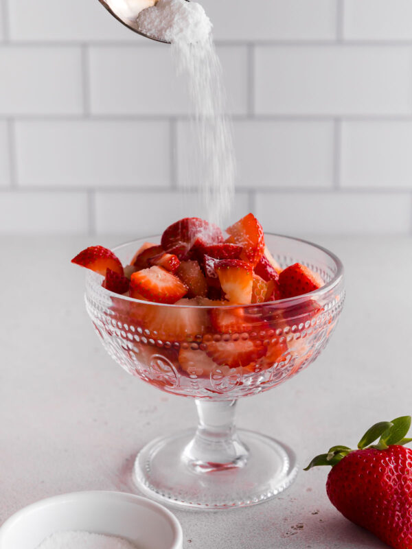 sprinkling sugar over sliced strawberries