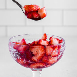 scooping out macerated strawberries from a bowl, using a spoon