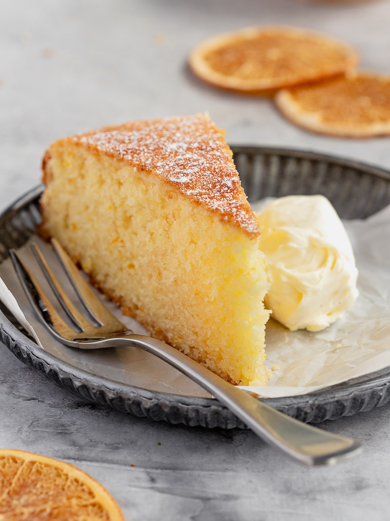 A wedge of soft and moist orange cake, served with chantilly cream.