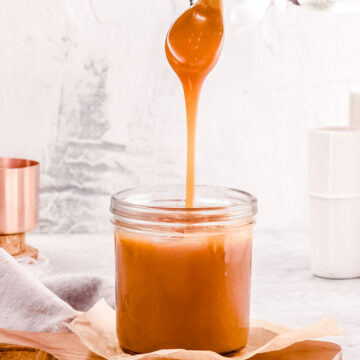 Drizzling homemade salted caramel into a glass jar.