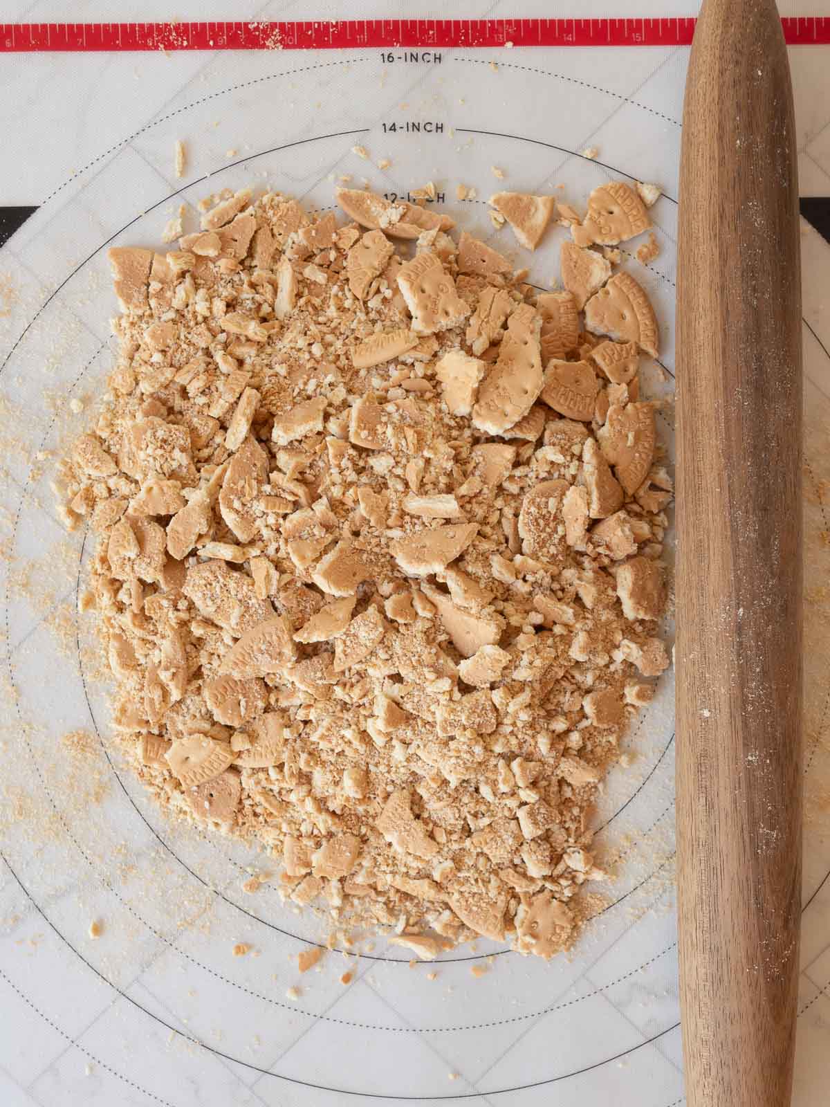 Crushing marie biscuits with a rolling pin.