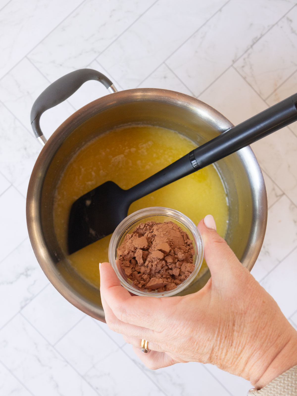 Adding cocoa to the melted butter.