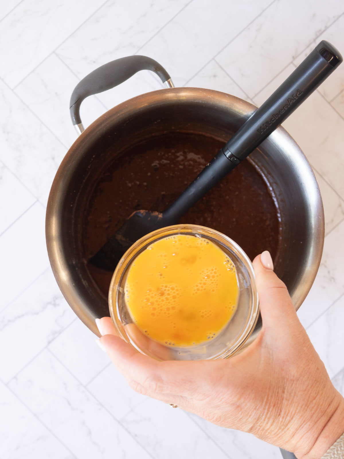 Adding the beaten egg to the chocolate mixture.