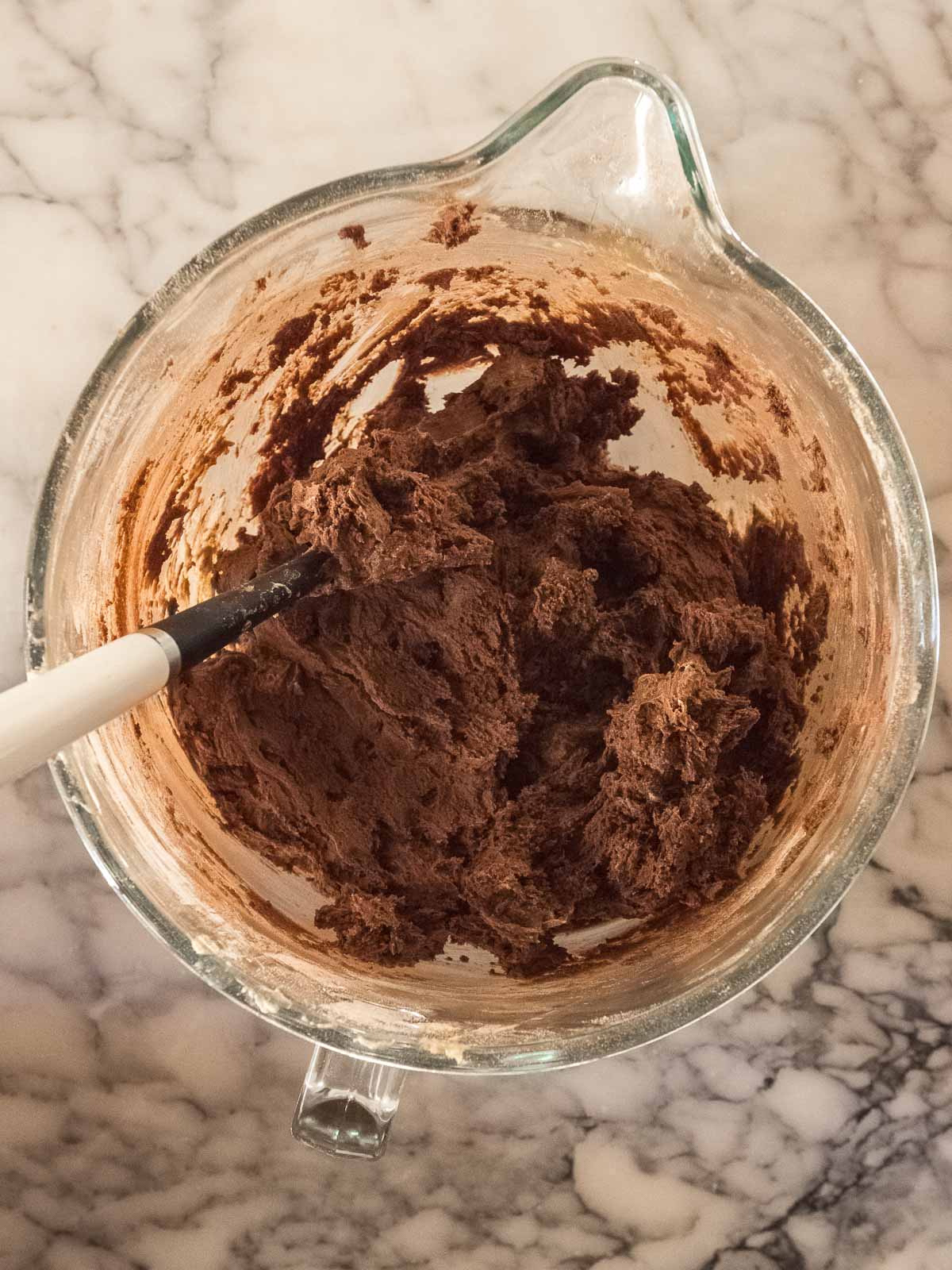 Sifted cocoa powder, flour, and baking soda mixed into wet ingredients for double chocolate cookie dough with gooey marshmallow centers.