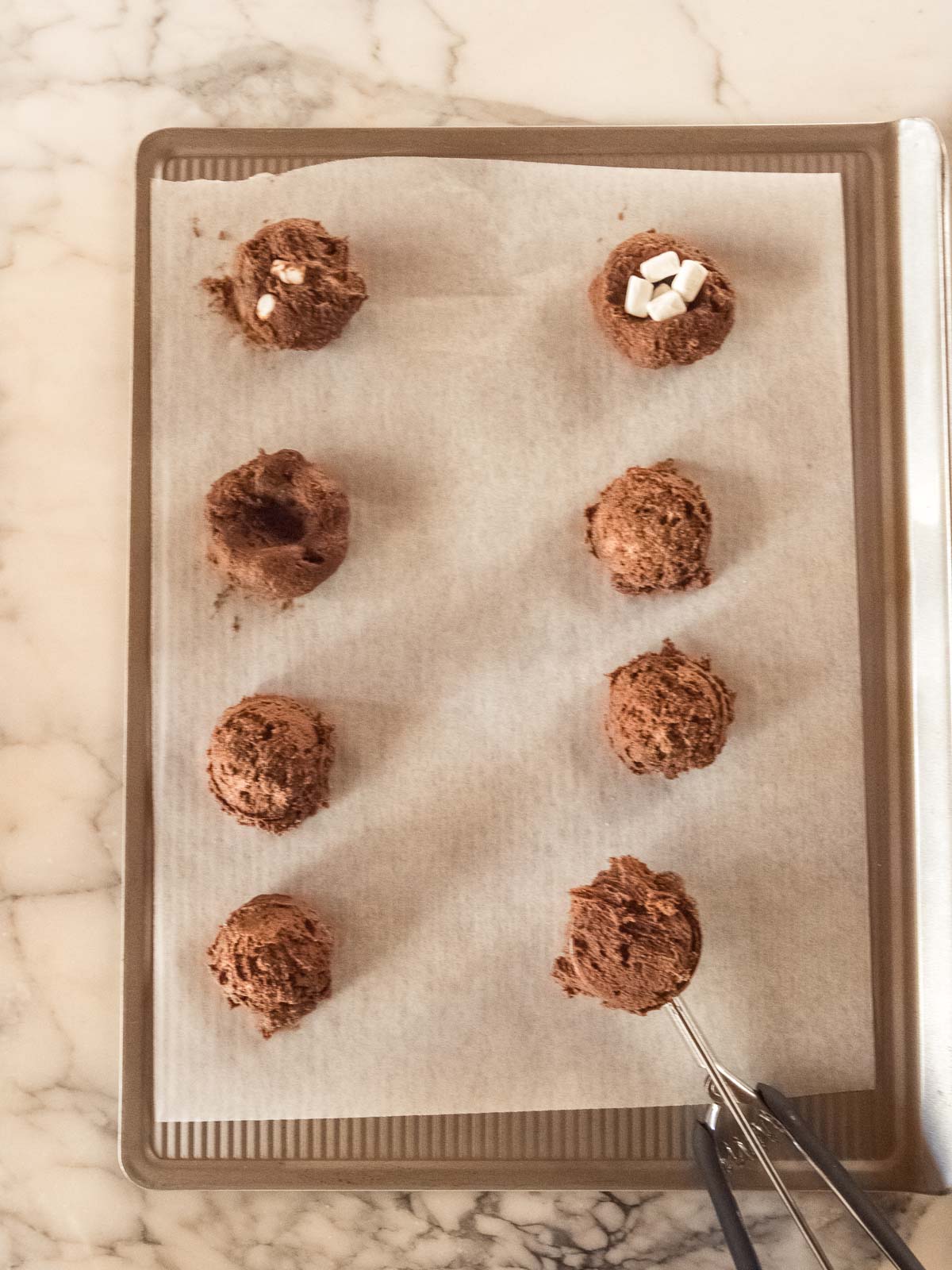 Scooping balls of chocolate cookie dough onto lined baking tray before adding marshmallows – no chill chocolate cookie recipe.