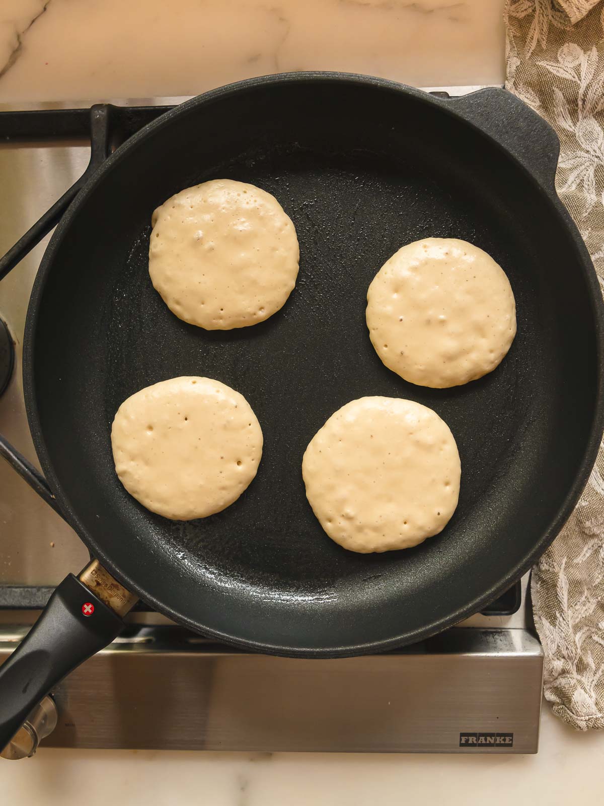 Cooking the pikelets over low heat until bubbles pop and the batter no longer looks wet.