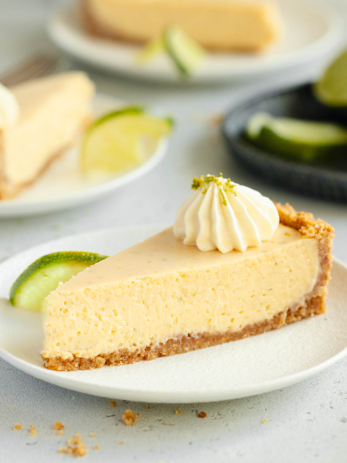 A slice of gluten-free Key Lime Pie with whipped cream and lime zest, ready to be enjoyed.