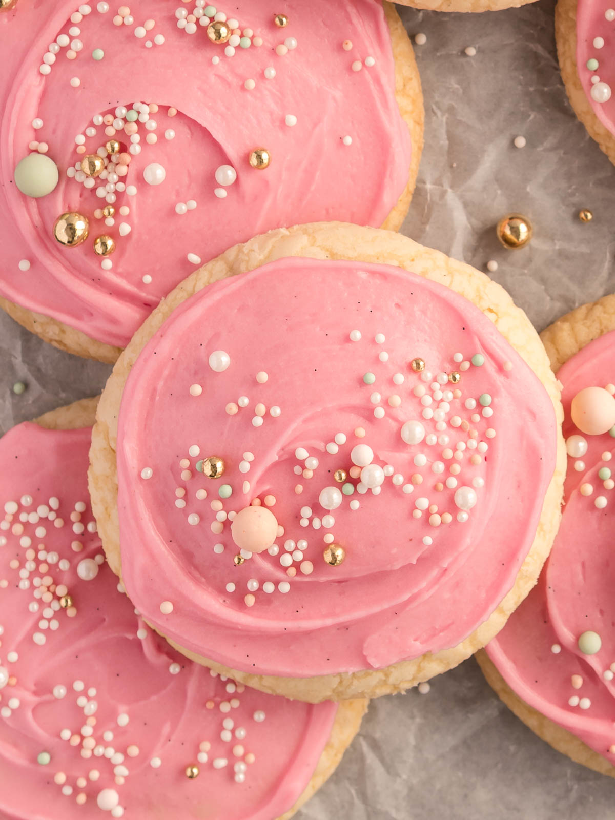 A tray of soft, pink frosted sugar cookies topped with colourful sprinkles – bakery-style cookies with thick, pillowy centres