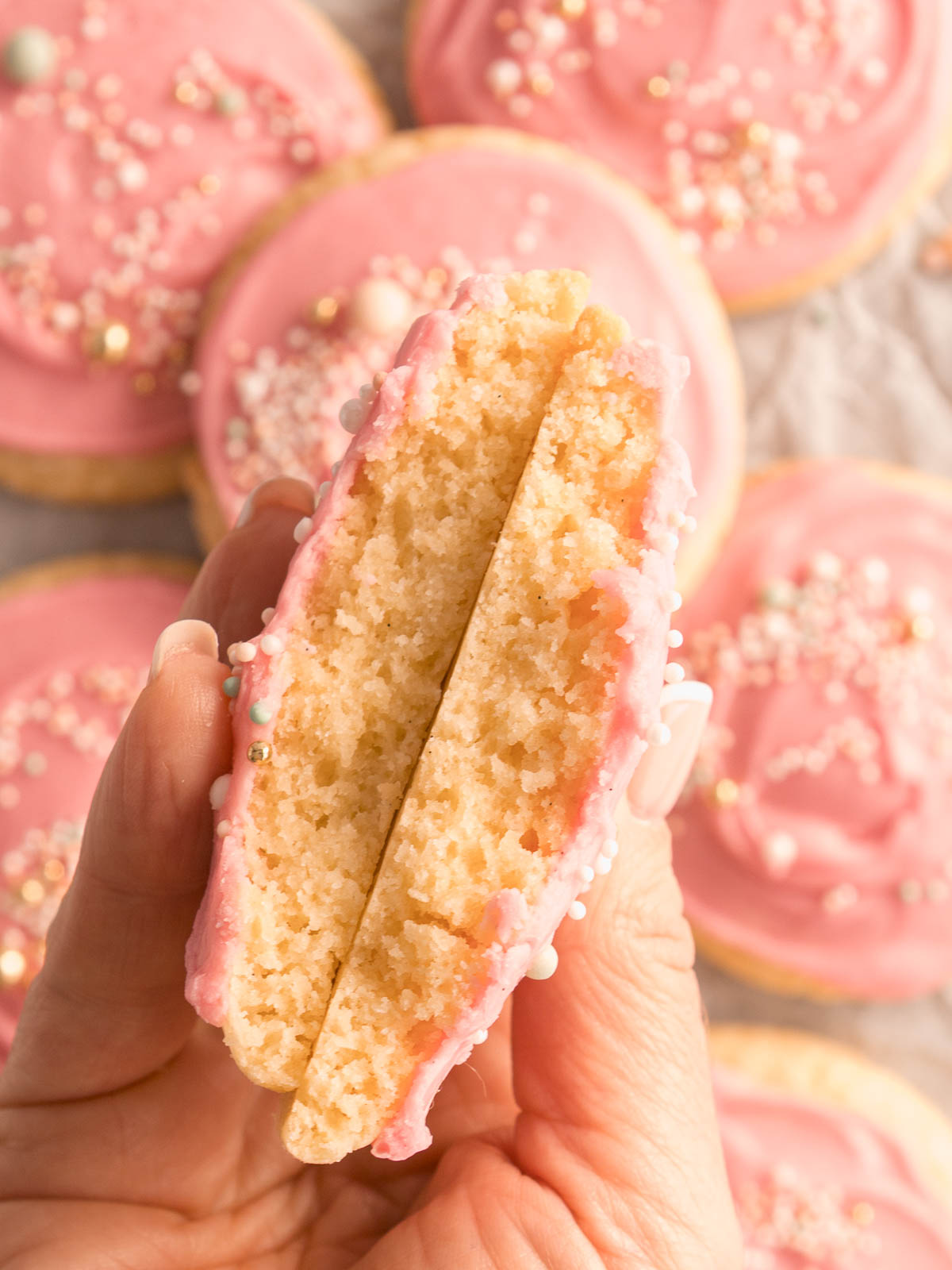 A tray of soft, pink frosted sugar cookies topped with colourful sprinkles – bakery-style cookies with thick, pillowy centres
